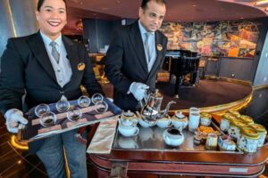 Two butlers serve afternoon tea in the Yacht Club lounge on the MSC Meraviglia