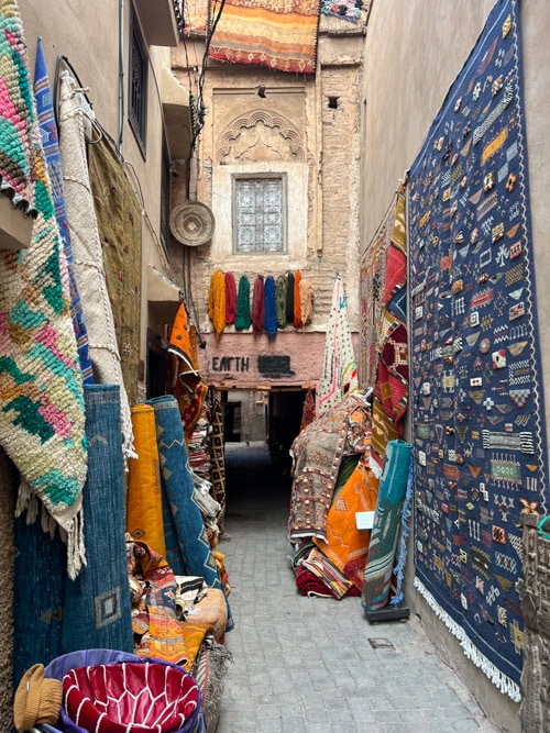 Handmade carpets outside a Marrakesh shop, showcasing vibrant colors and traditional craftsmanship.