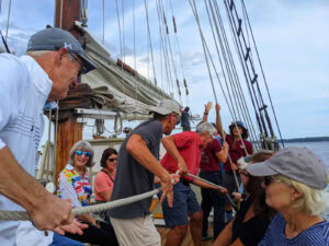 The author (reverse ballcap) and others help to raise the main sail on the 114' schooner Manitou