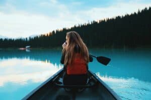 Woman paddling in a canoe by Roberto Nickson